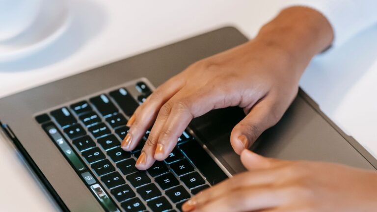 Dłonie piszące na laptopie obok kawy, praca nad maile z pytań klientek